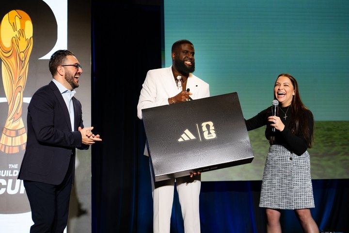 Three people smiling during an onstage gift presentation