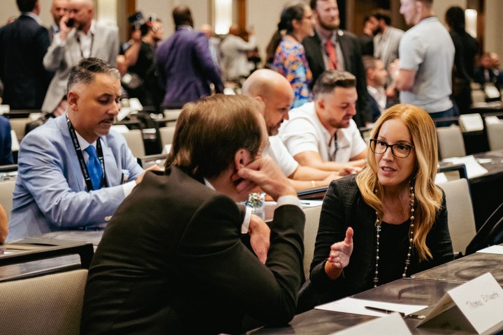 A woman speaking with a man during a busy conference breakout session