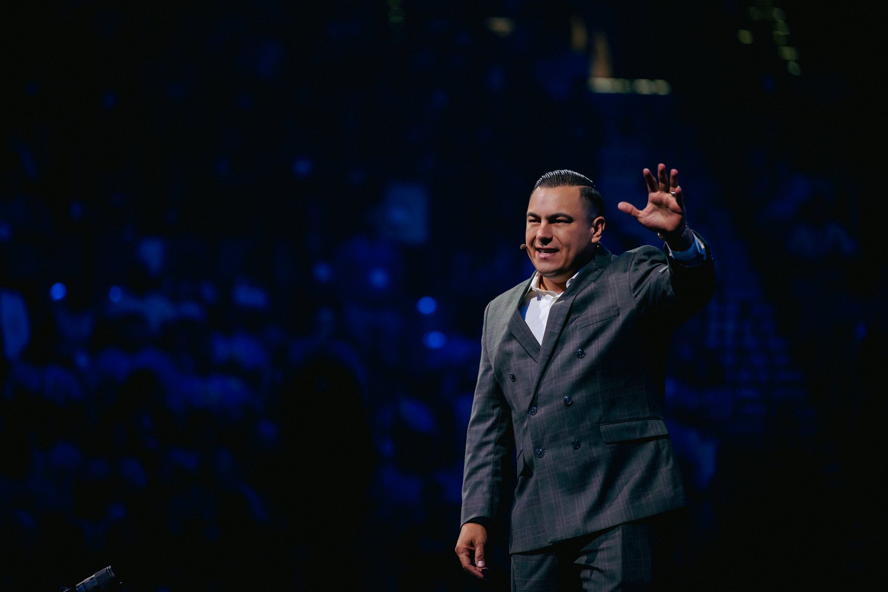 A speaker raising one hand against a dark blue audience at Big Event 2025