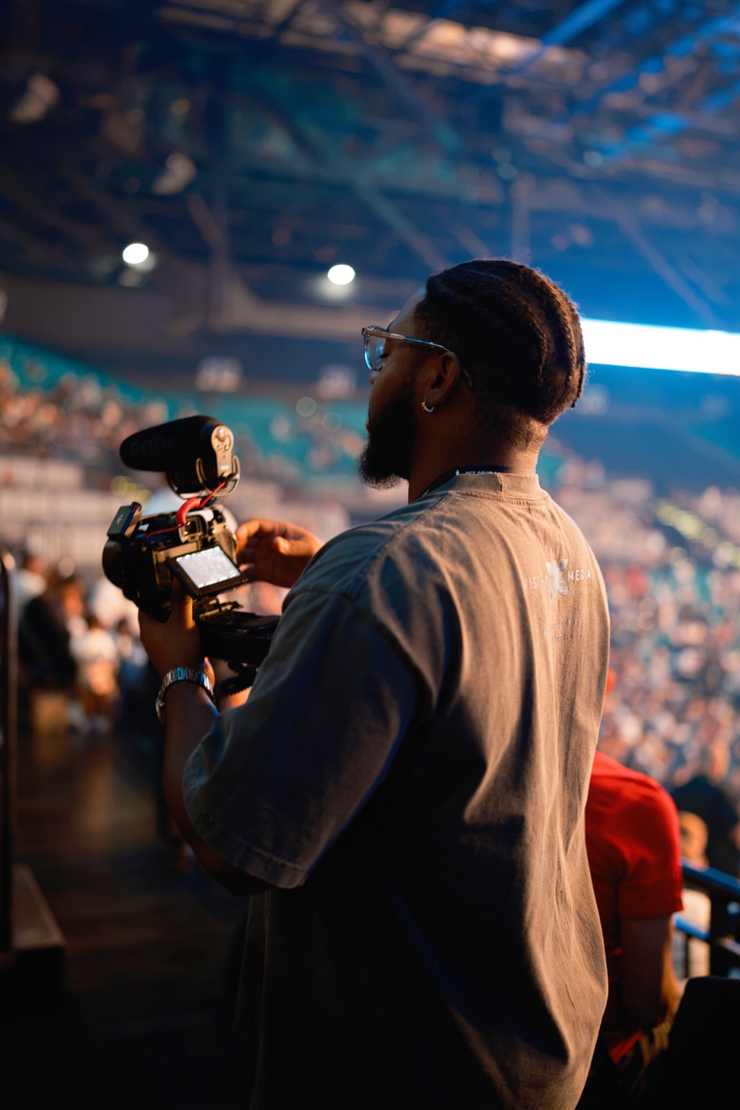 A Visionx videographer filming inside a busy event arena