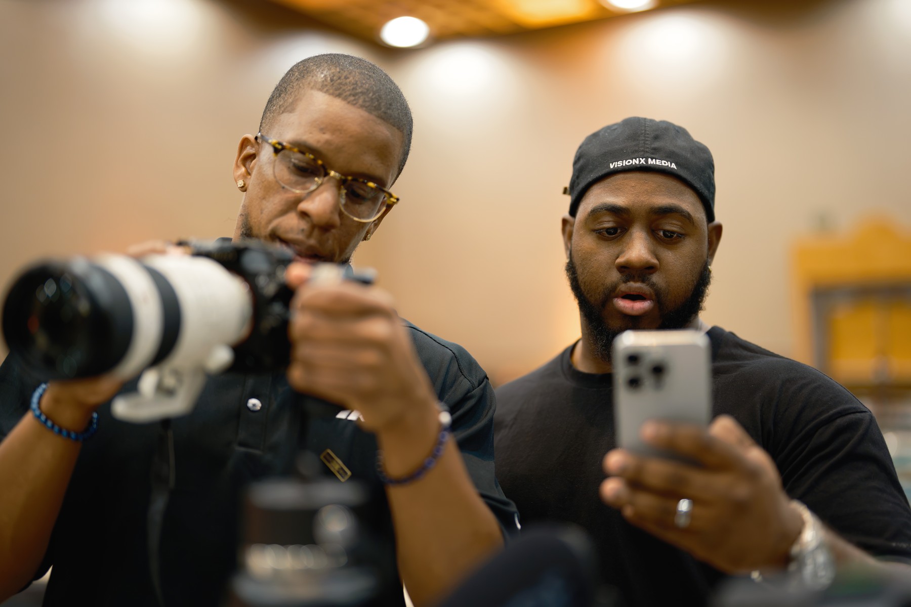Two crew members checking a long-lens camera and phone at Vault 2026