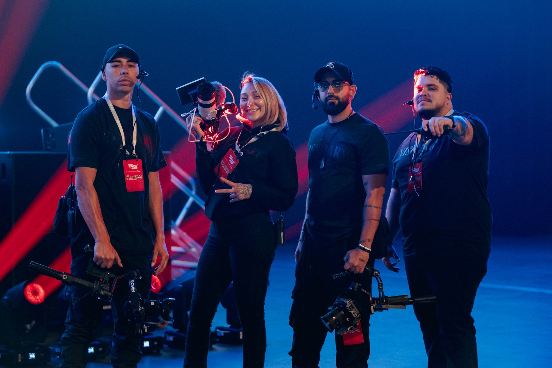 Four Visionx crew members with camera rigs under blue and red stage lights